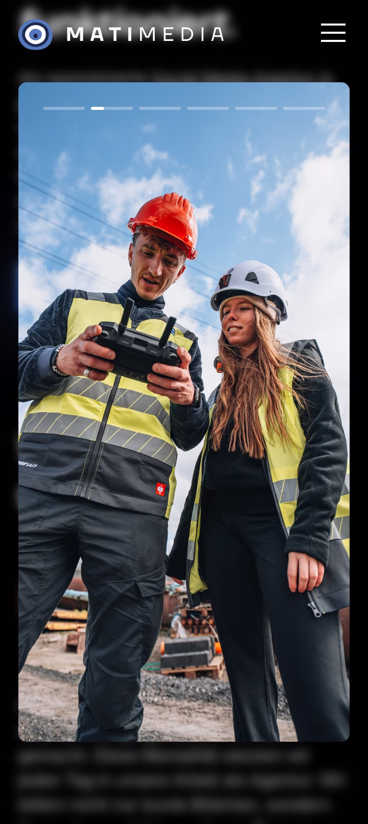 Zwei Bauarbeiter mit Helmen und Warnwesten bedienen eine Drohnenfernbedienung auf einer Baustelle.