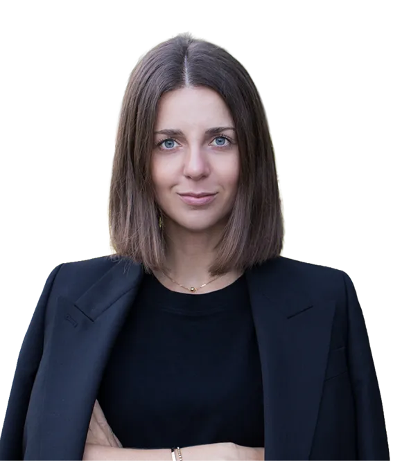 Woman with straight brown hair wearing a black blazer and black top, looking confidently at the camera.