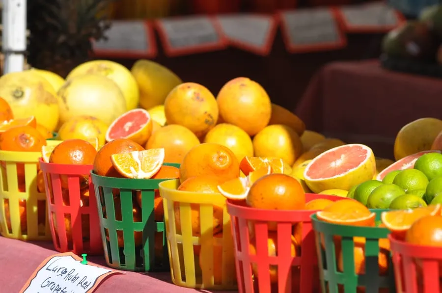 Colorful baskets of fresh citrus fruits including oranges, limes, grapefruits, and pomelos displayed at a market stand.