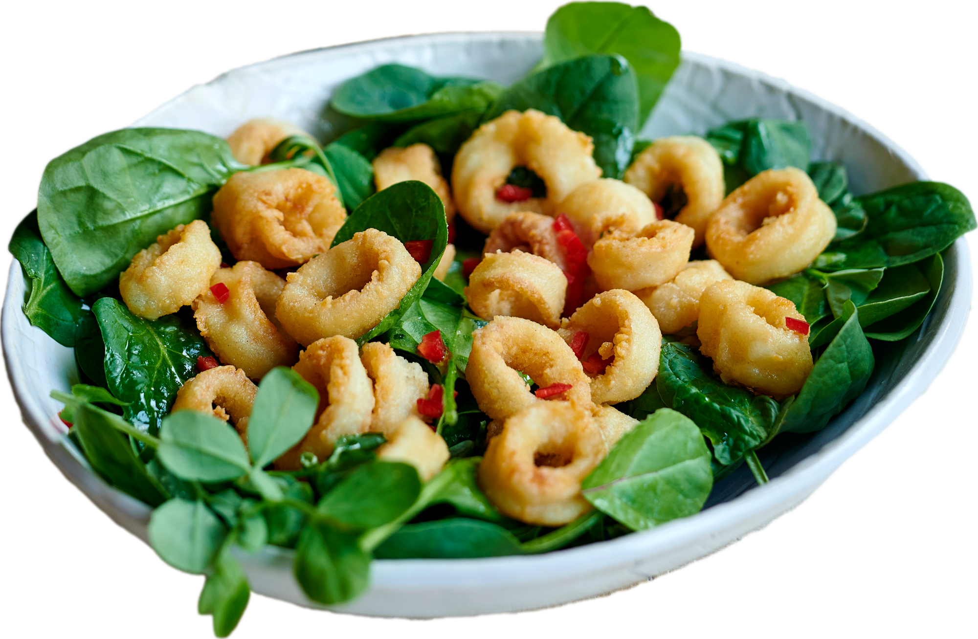 White bowl with fried calamari rings on a bed of fresh spinach leaves and small pieces of red pepper.