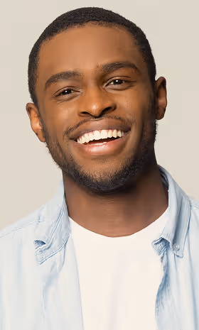Young man smiling with teeth visible wearing light blue shirt over white t-shirt.