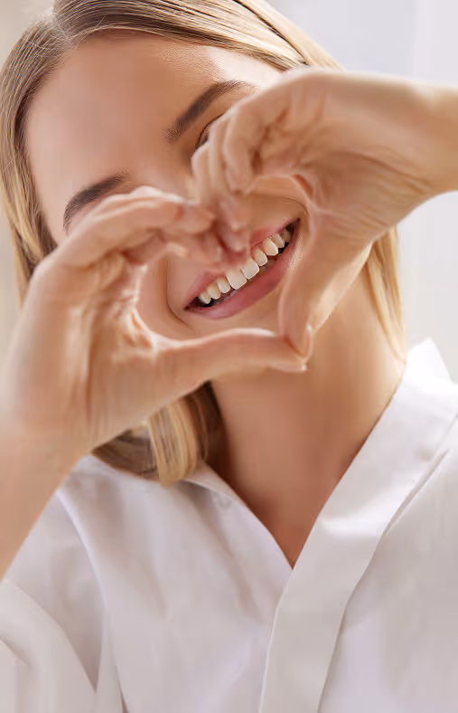 Smiling woman forming a heart shape with her hands close to her face.