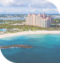 Tall resort buildings near a sandy beach with turquoise ocean and clear sky.