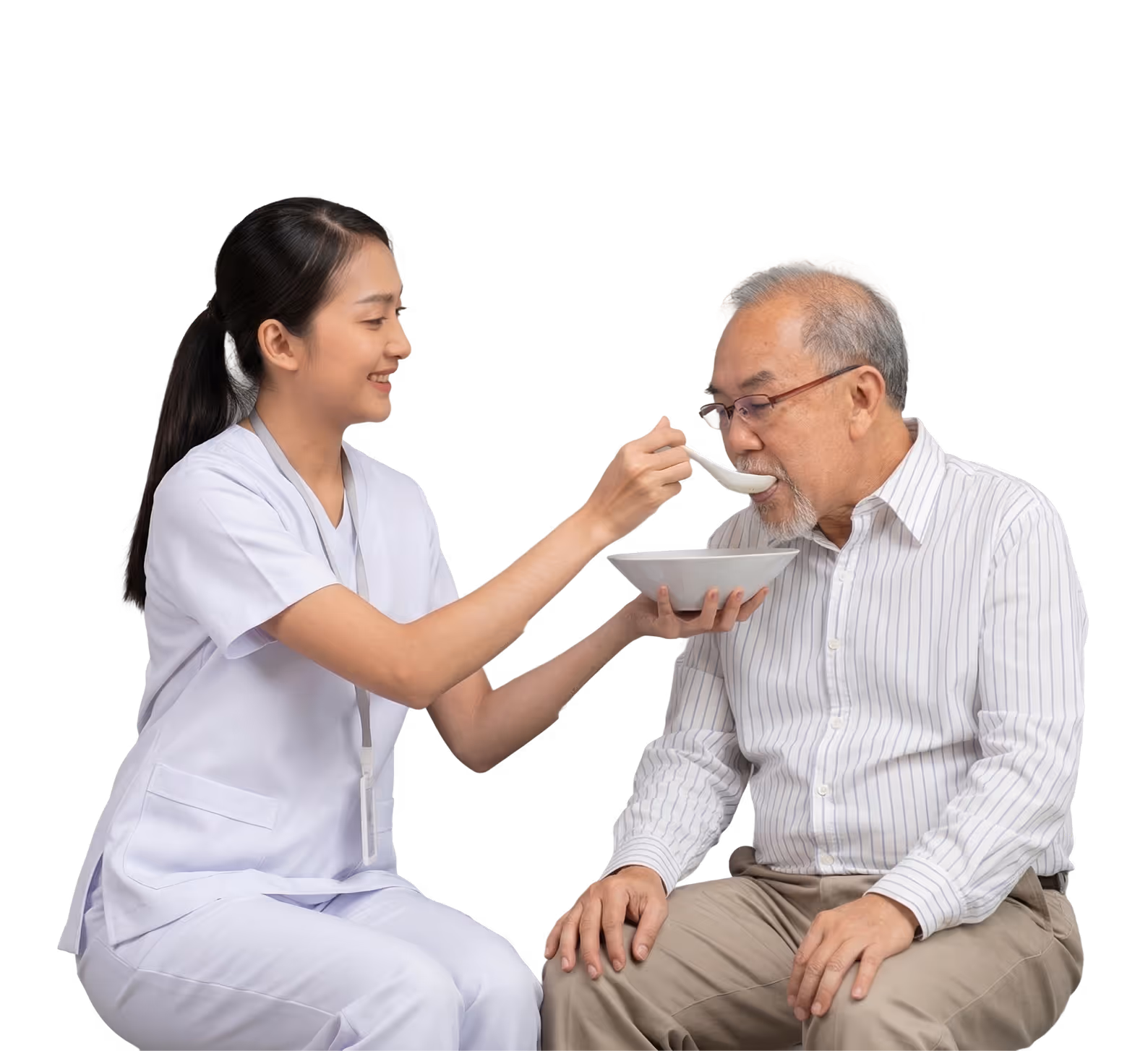 Nurse in white uniform feeding elderly man soup with a spoon while holding a bowl.
