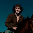 A man riding on the back of a brown horse.