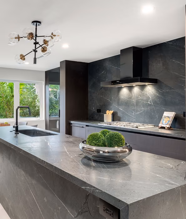 Modern kitchen with marble island, black stove hood,  by MT Construction Miami