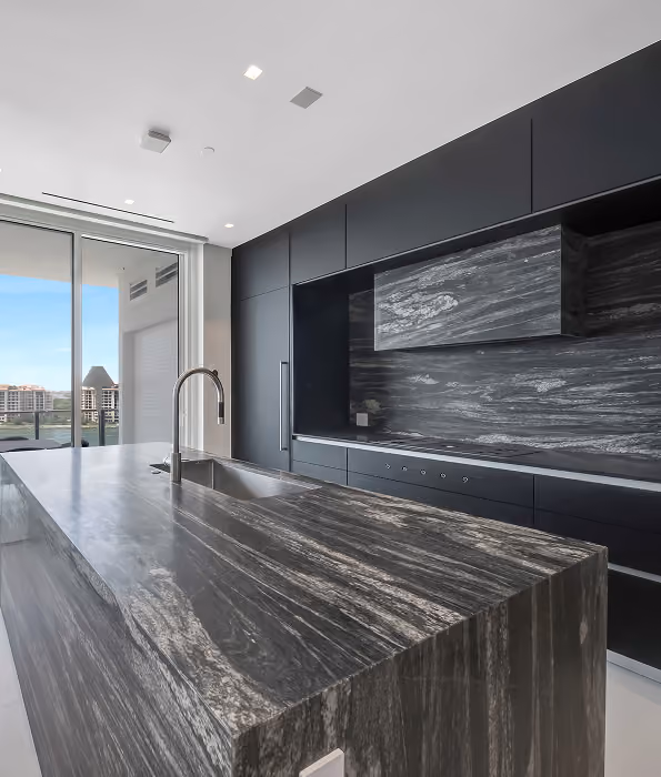 Modern kitchen with large black marble island,  by MT Construction Miami