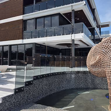 Modern building with glass railings and pool area  by MT Construction Miami