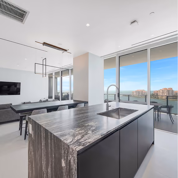 Modern kitchen island with sink and dark marble countertop by MT Construction Group Miami