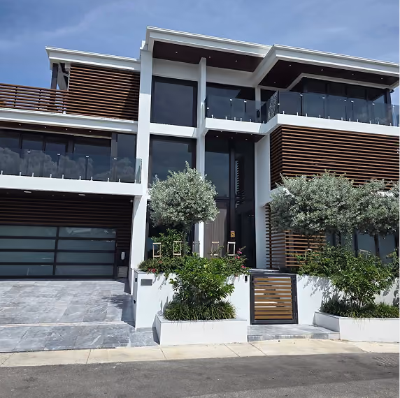 Modern two-story house with large glass windows, by MT Construction Group Miami