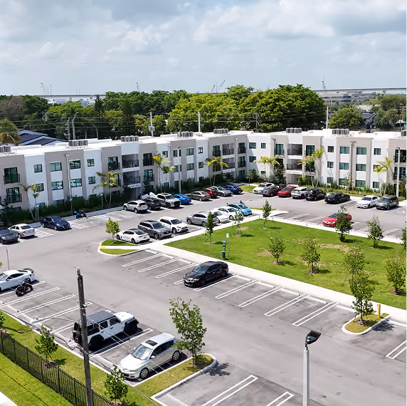 A modern apartment complex with a parking lot,by MT Construction Group Miami