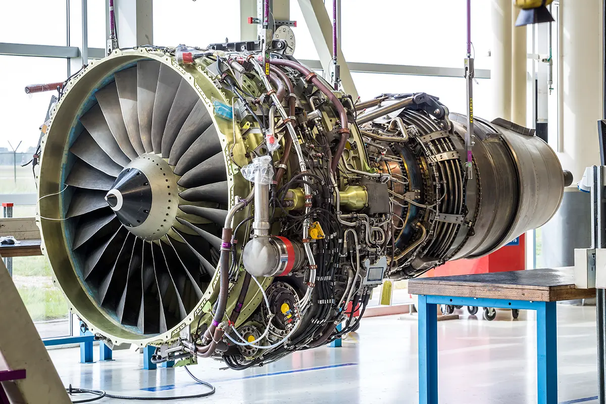 Large aircraft jet engine displayed indoors, showing detailed internal turbine blades and mechanical components.