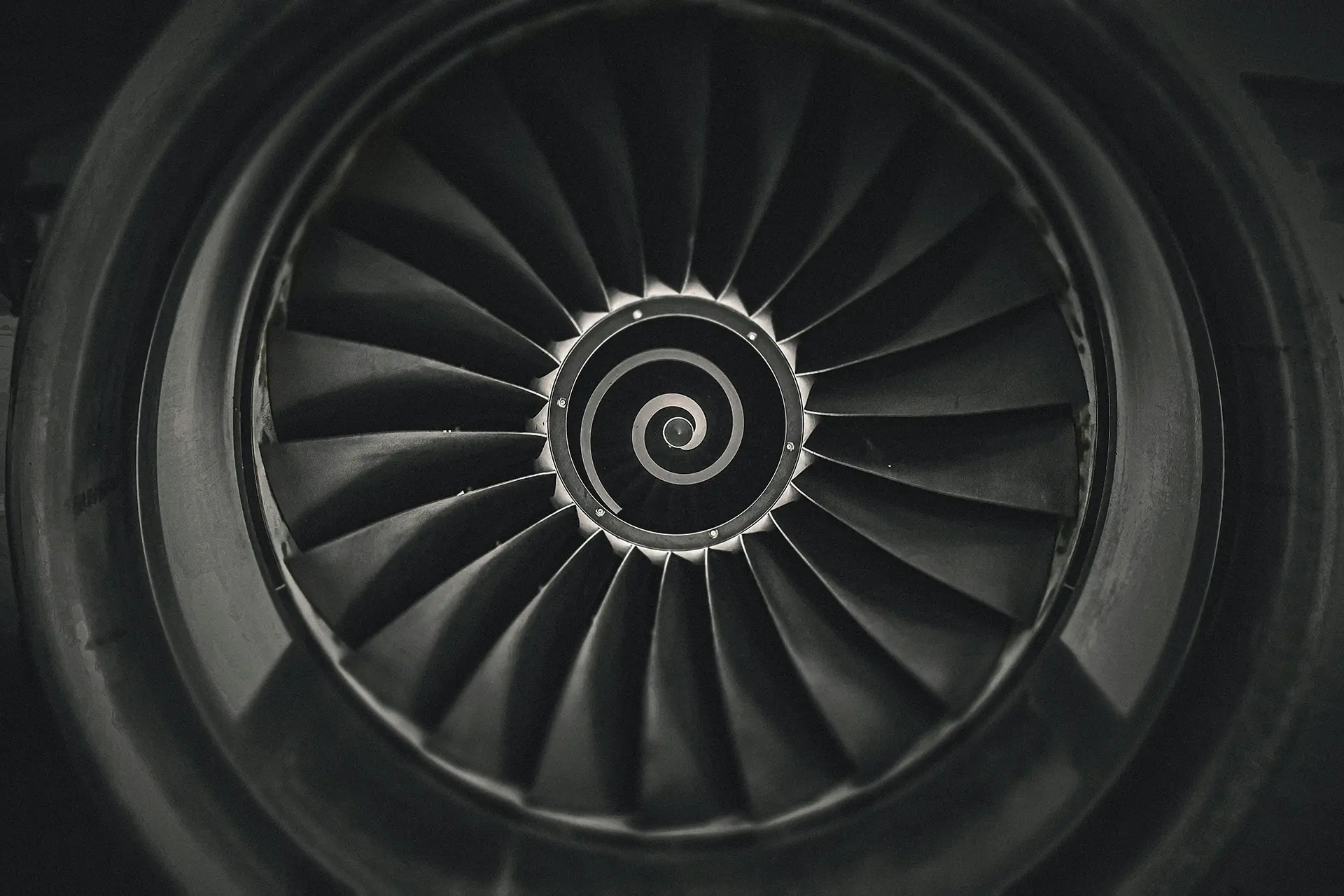 Close-up of the blades and spiral design at the centre of a jet engine turbine.