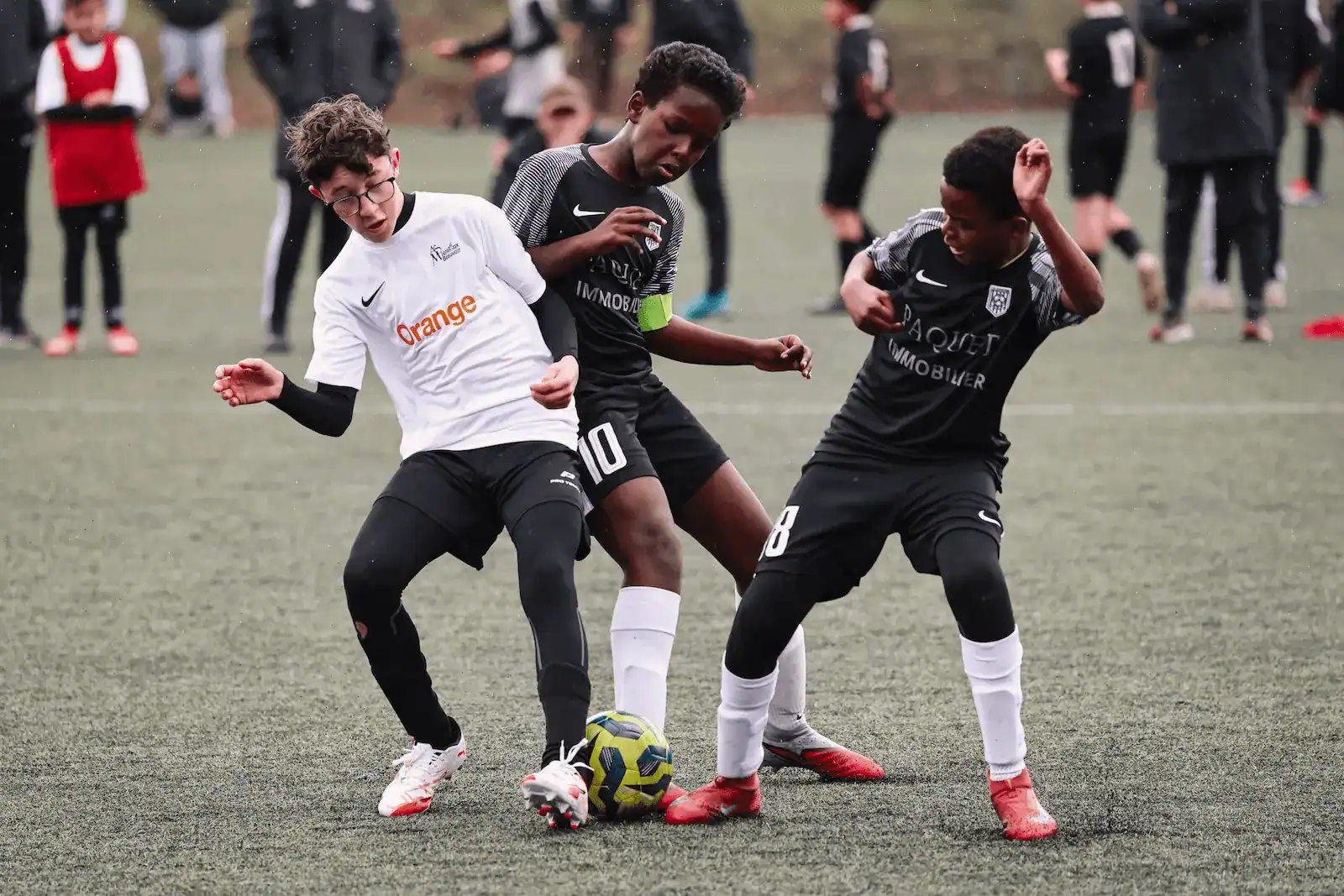 Photographie d’adolescents jouant au football et se disputant le ballon lors d’un match d’une équipe enfant de La Ligugéenne, avec leurs pieds.