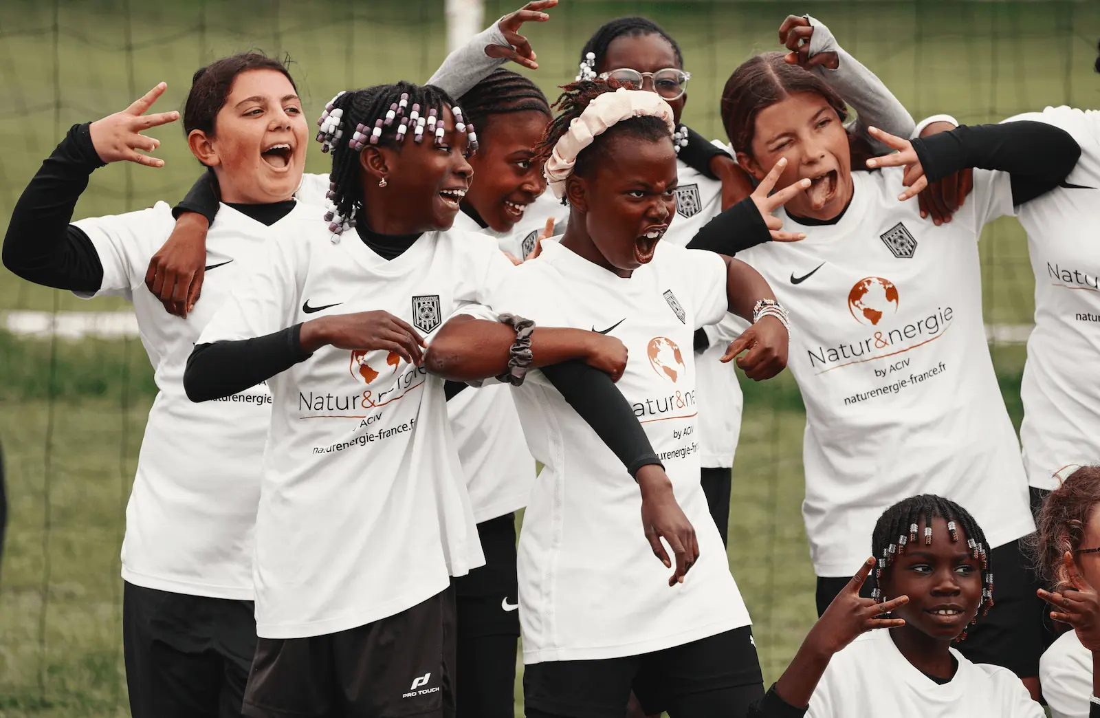 Photographie d’une équipe de football féminine junior du club La Ligugéenne en train de poser devant un but. Sur leur maillot, on aperçoit leur sponsor : Natur&nergie.