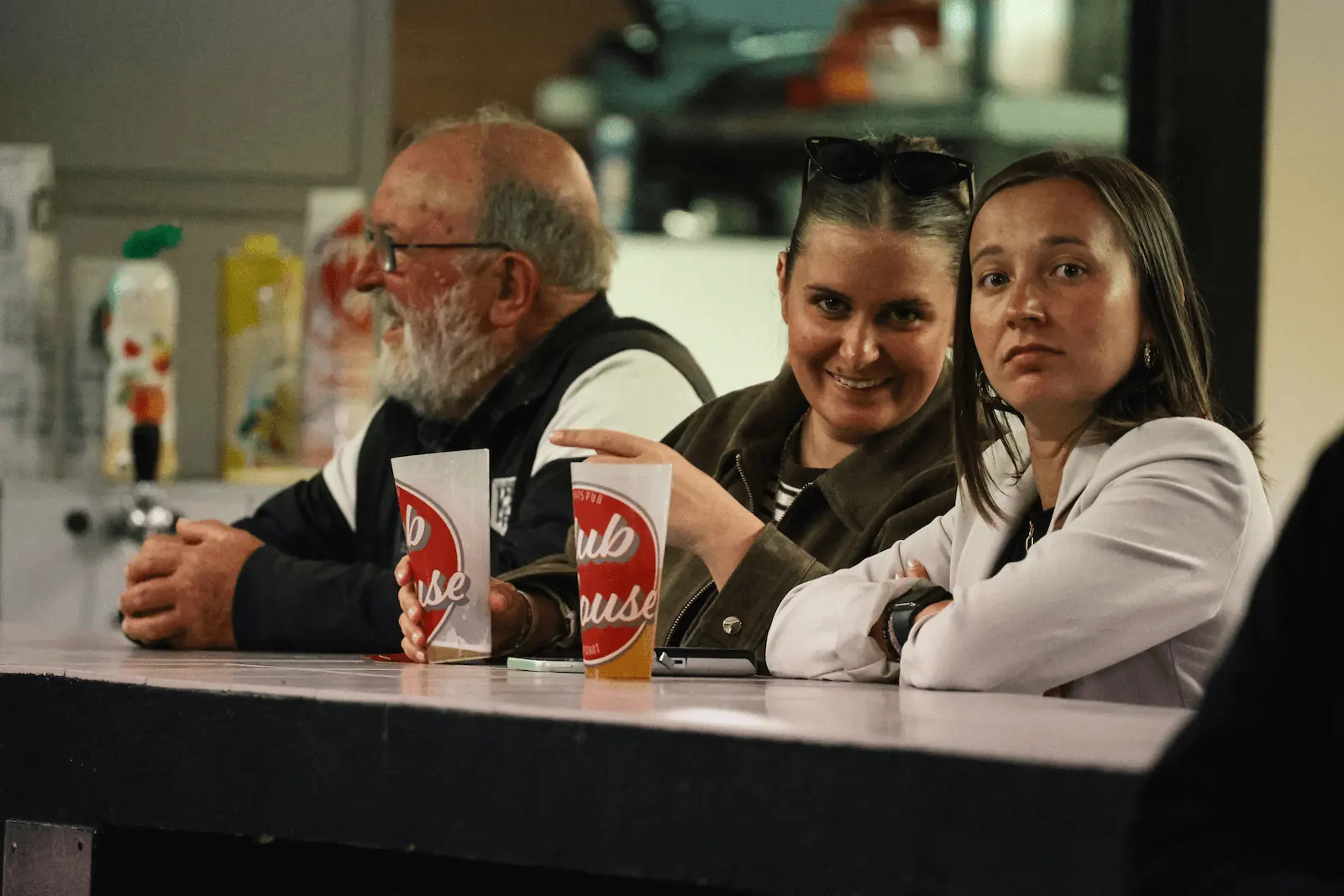 Photographie de deux femmes supportrices de la Ligugéenne qui boivent une bière sur un comptoir de bar en regardant l’objectif