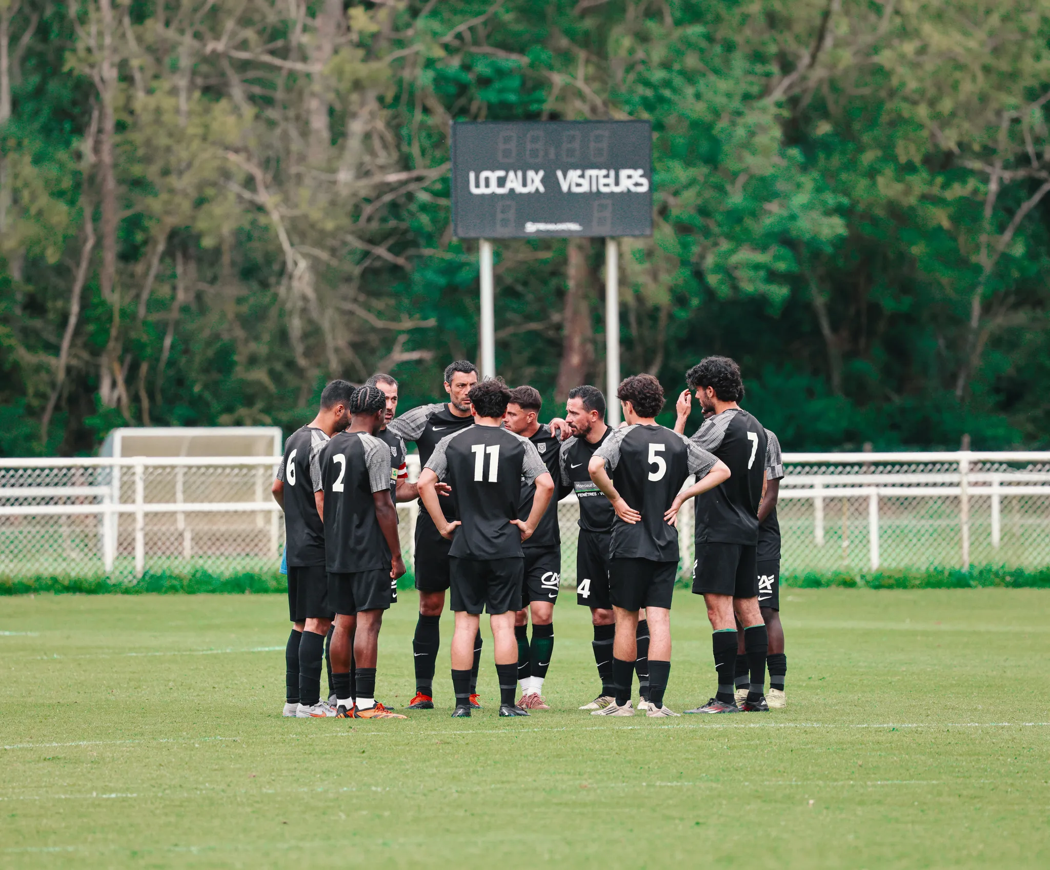 Photo de l'équipe de R2 de La Ligugéenne regroupée en cercle sur un terrain de foot
