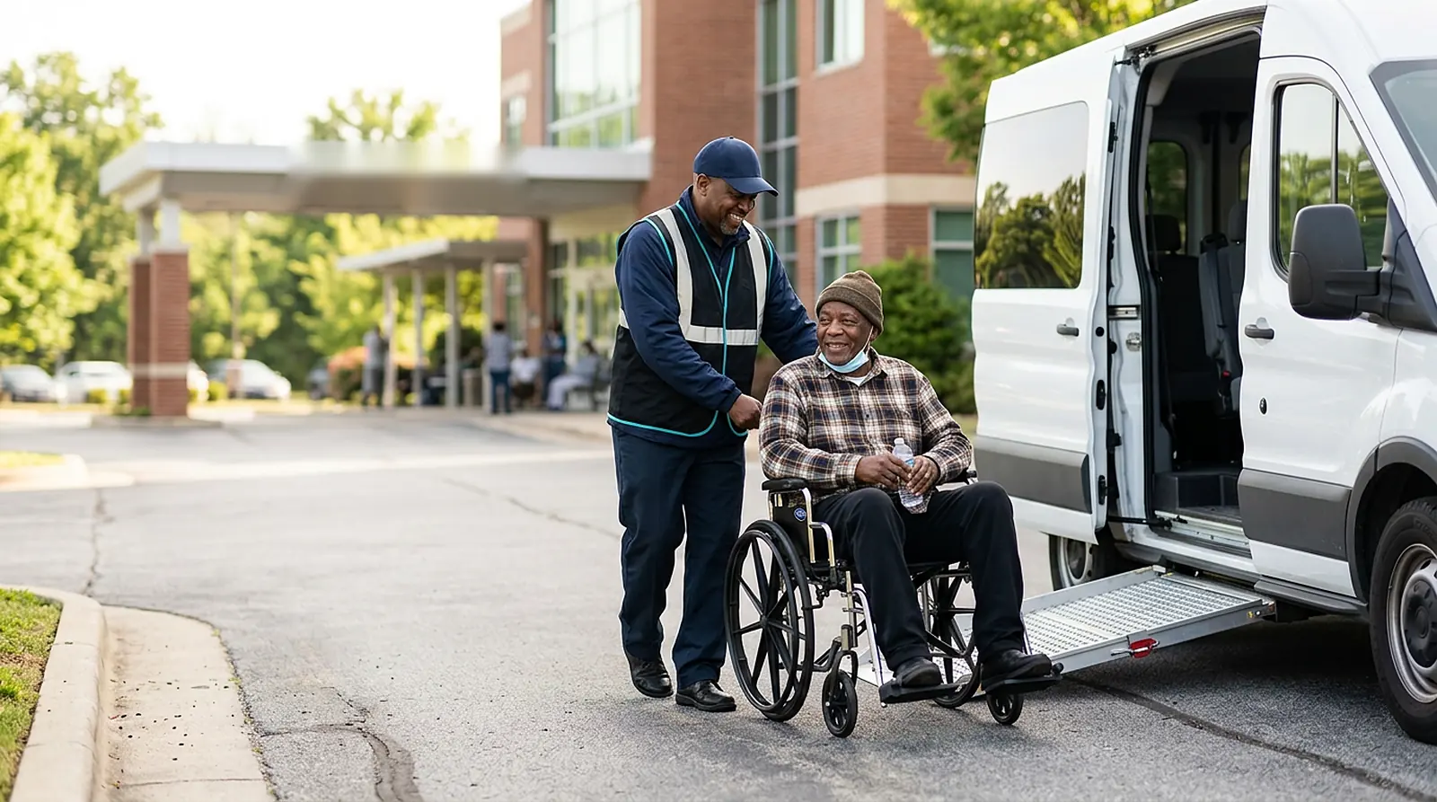 NEMT driver greeting a wheelchair passenger beside an accessible van at a dialysis center in morning sun