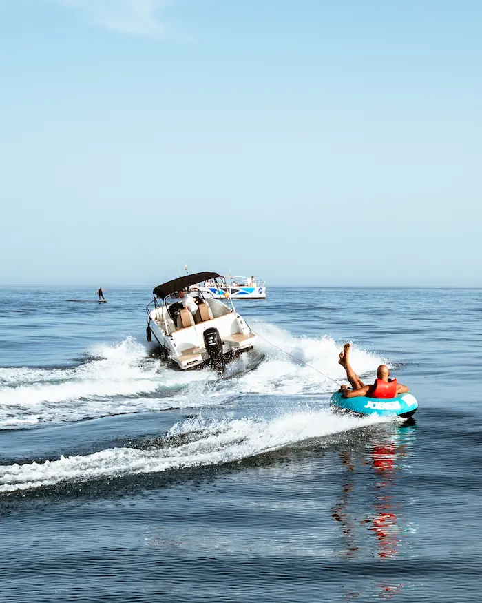 Lancha llevando a un hombre montado en un rosco flotador