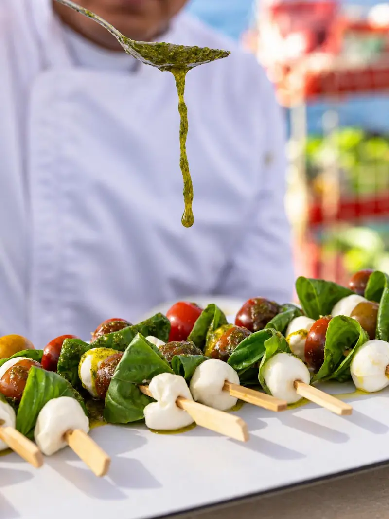 Hombre preparando pinchos de mozzarella y verduras a bordo del catamarán Serenity