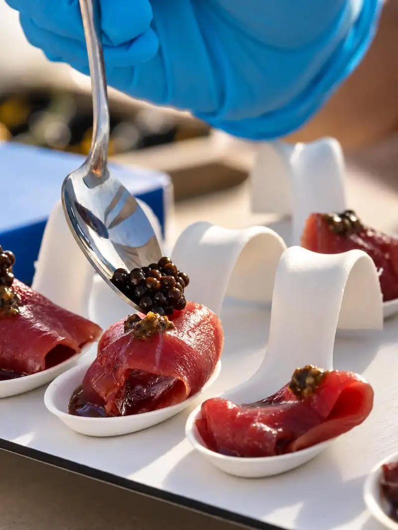 Cuchara poniendo caviar en tapas de tartar