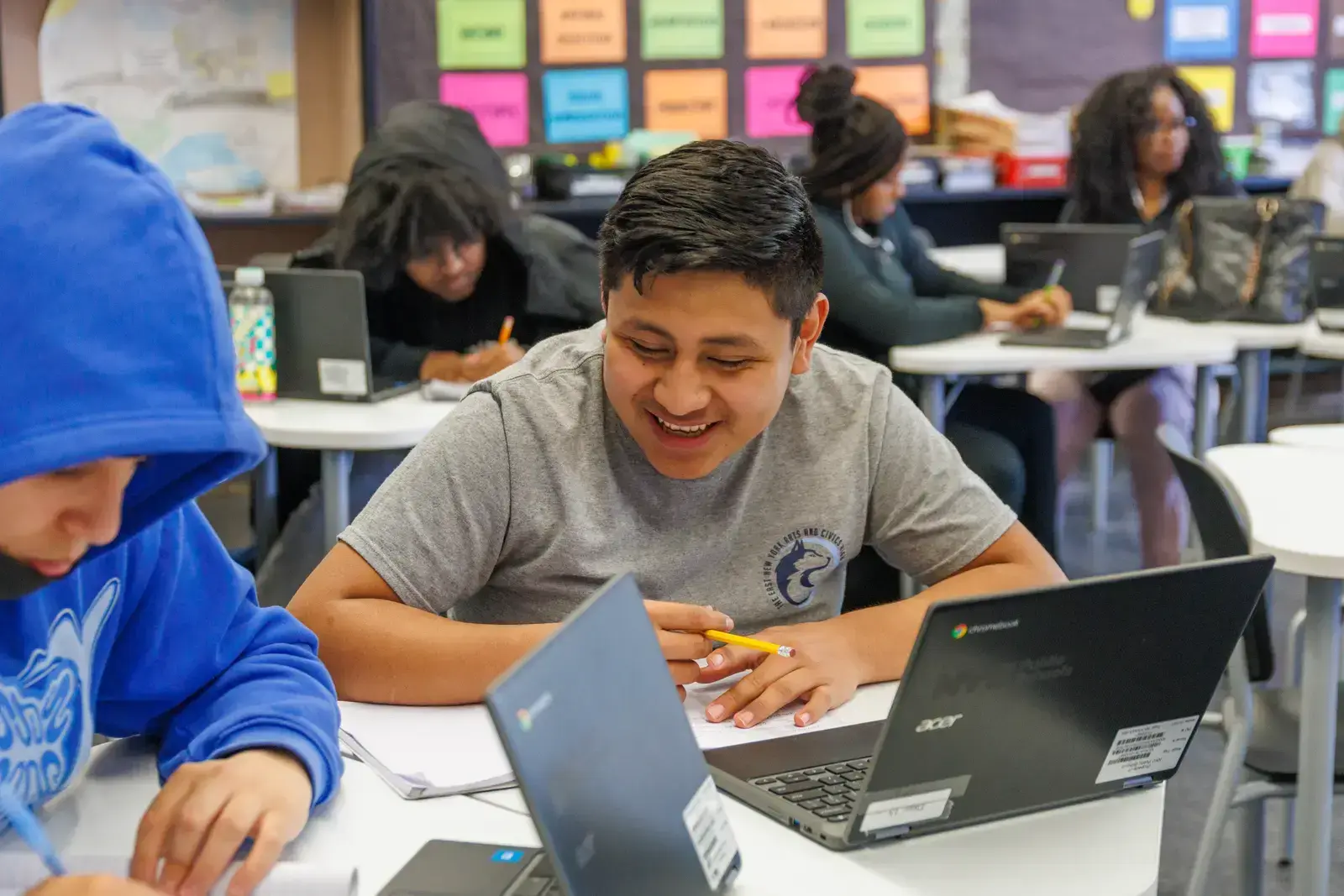 Smiling student working on laptop and notes in classroom