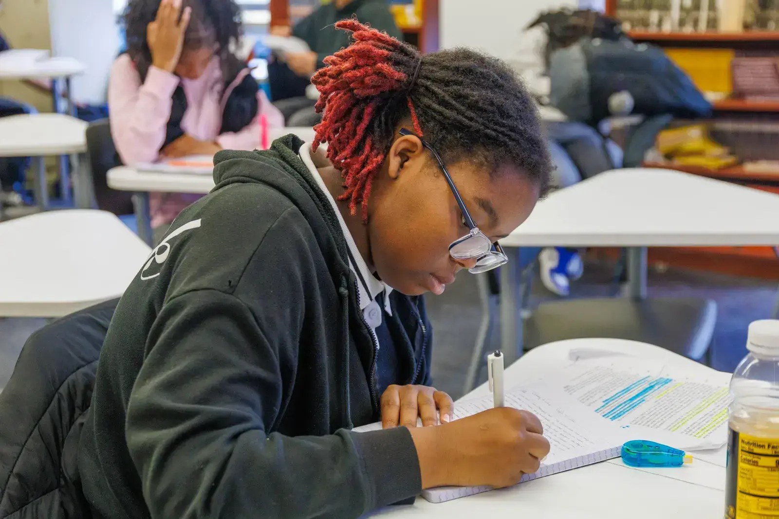 Student writing in notebook at classroom desk during lesson