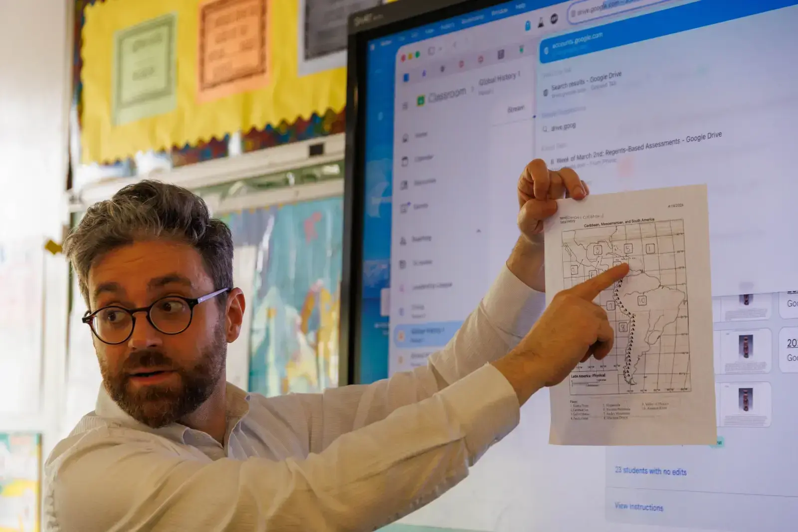 Teacher pointing to a Latin America physical map during class instruction