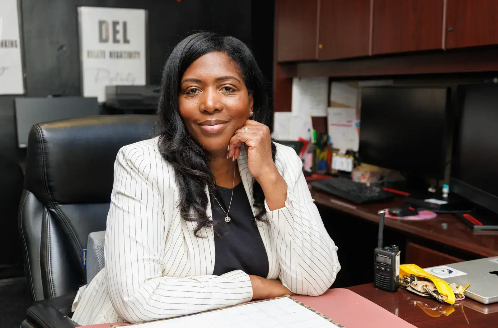 Principal Dr. M. Davy seated at her office desk smiling