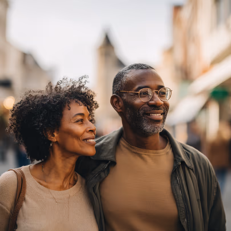 Middle-aged couple smiling and walking closely together on a city street.