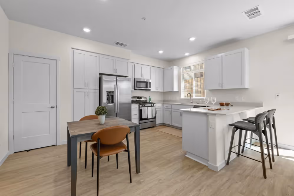Kitchen with white cabinets with dinning room and table with chairs