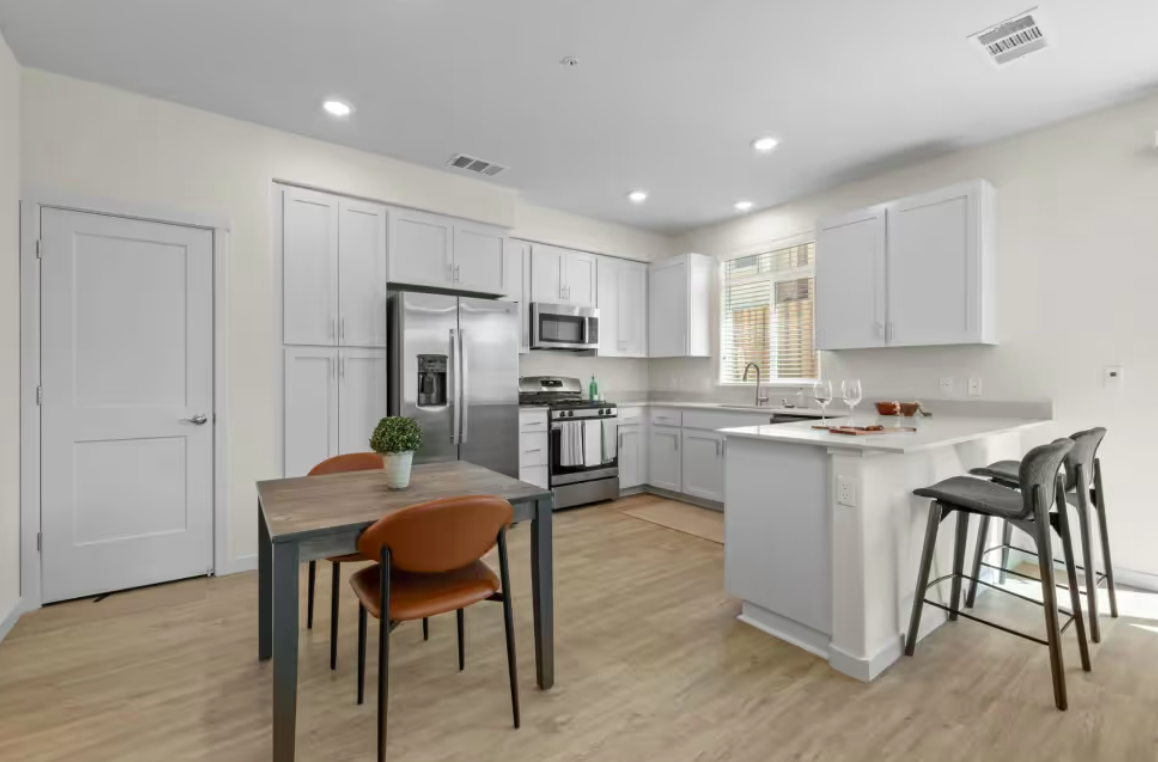 Kitchen with stainless steel appliances and a table with chairs.