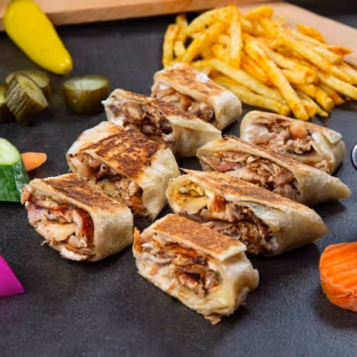 A sandwich with meat and vegetables on a black table.