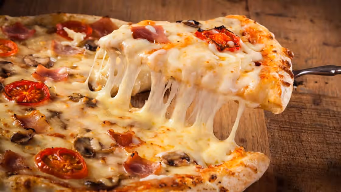 A slice of pizza with cheese and mushrooms on a wooden table.