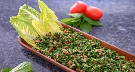 A wooden tray with a salad on it.