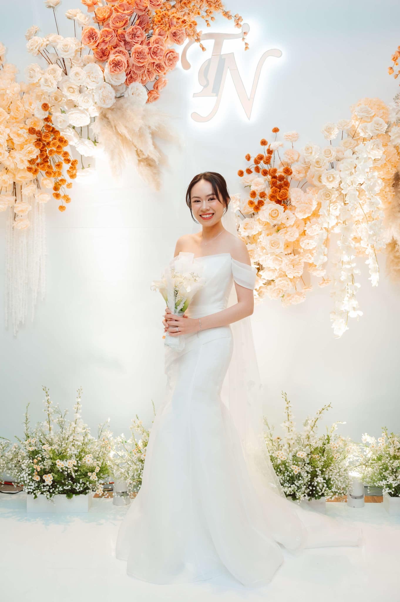 Bride in wedding gown standing in floral ceremony setup