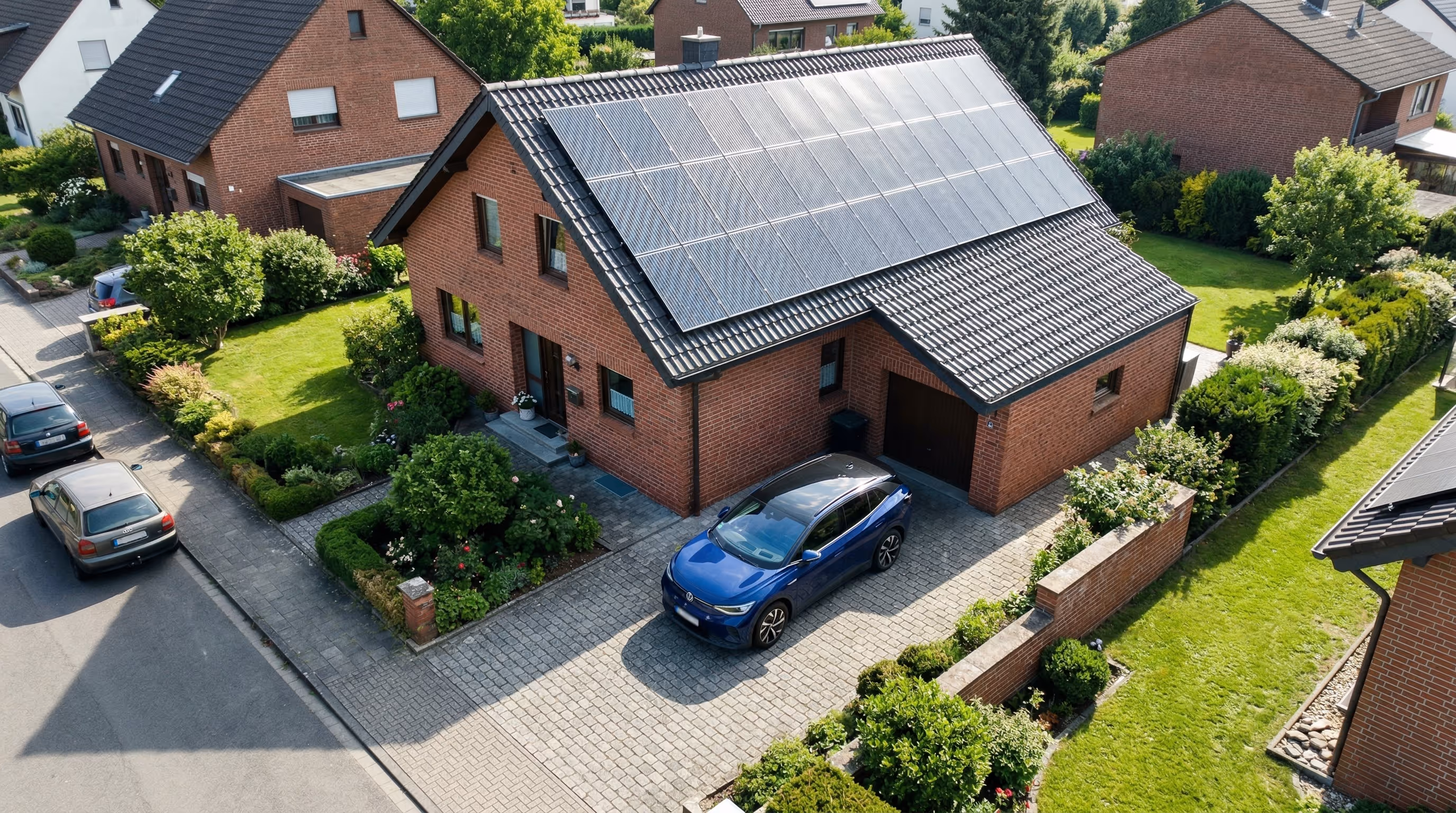 Backsteinhaus mit Solarpaneelen auf dem Dach und blauer Fahrzeugparkplatz in gepflegtem Garten.