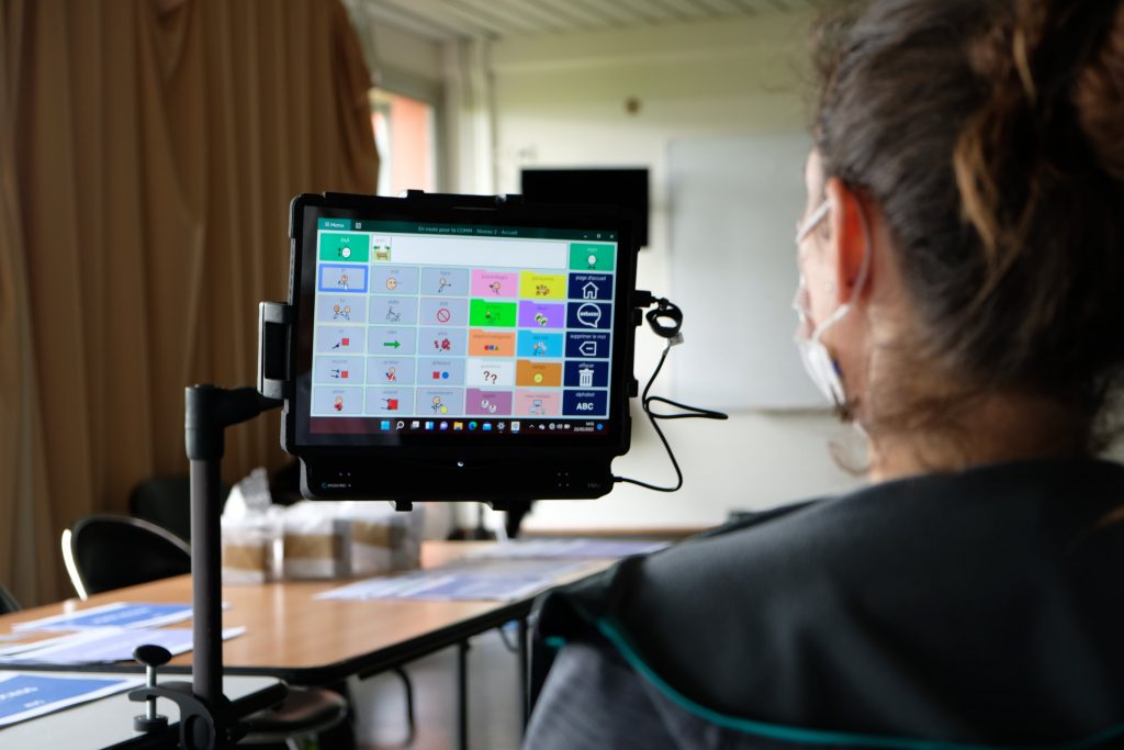 Femme de dos face à une tablette équipée d'une commande oculaire