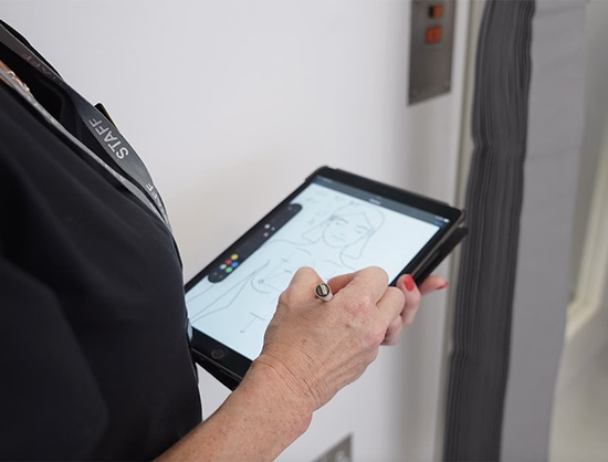 Person using a stylus to draw a human figure on a tablet screen.