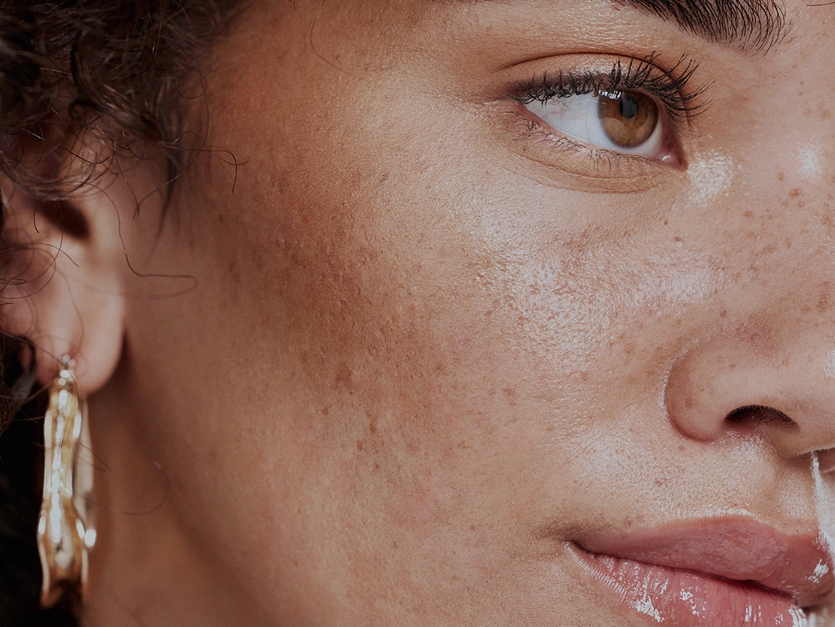 Close-up of a person's face highlighting natural skin texture and facial features, with prominent earrings.