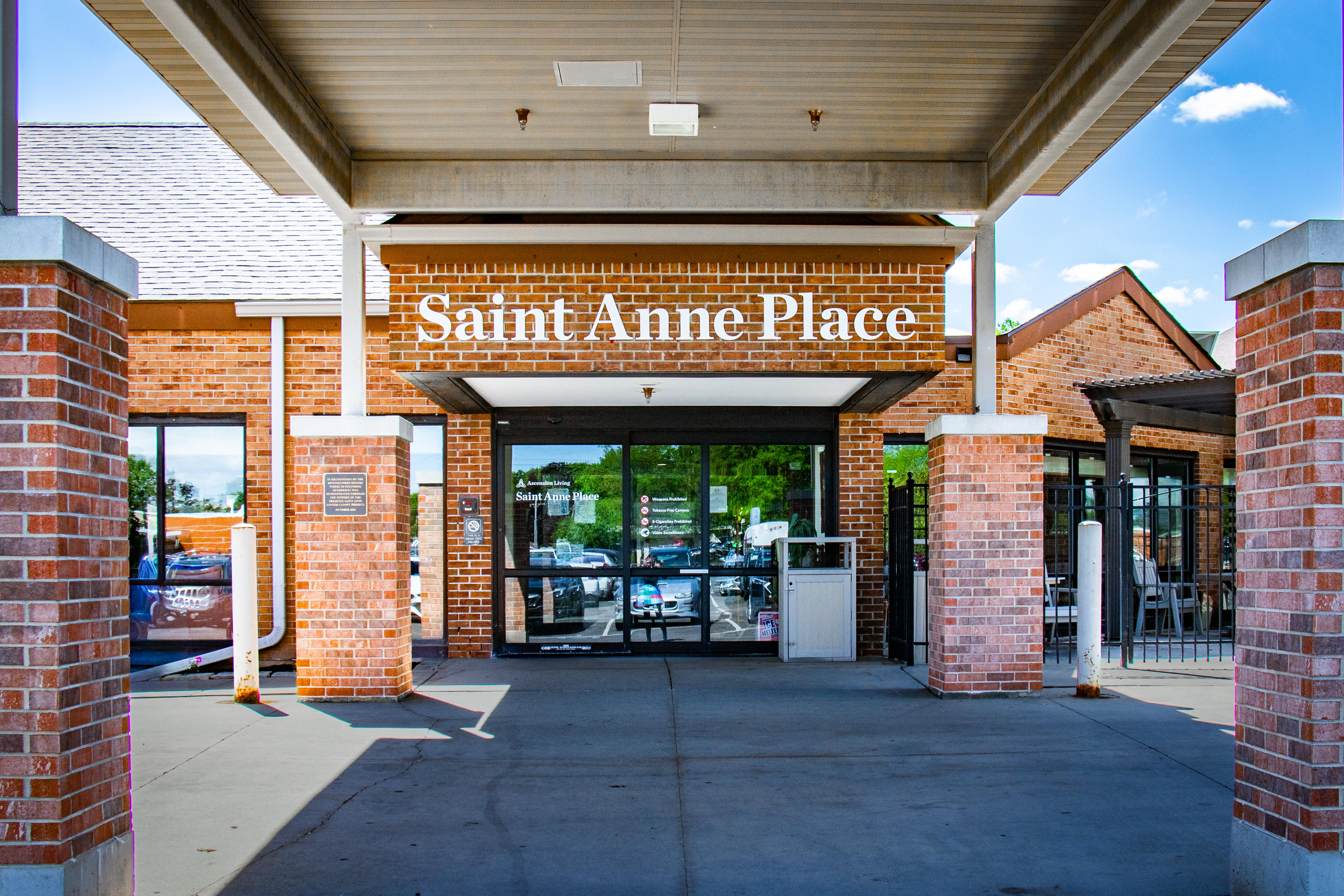 Entrance of Saint Anne Place with brick pillars and glass doors under a covered walkway.