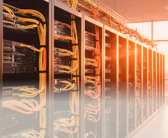 Row of server racks with organized network cables in a data center illuminated by warm sunlight.
