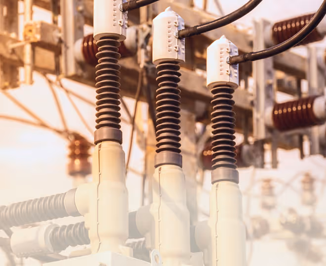 Close-up of high voltage electrical insulators and connectors at a power substation.