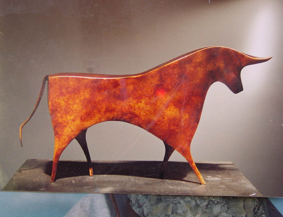 Rust-colored abstract metal sculpture of a bull with curved horns on a flat surface.