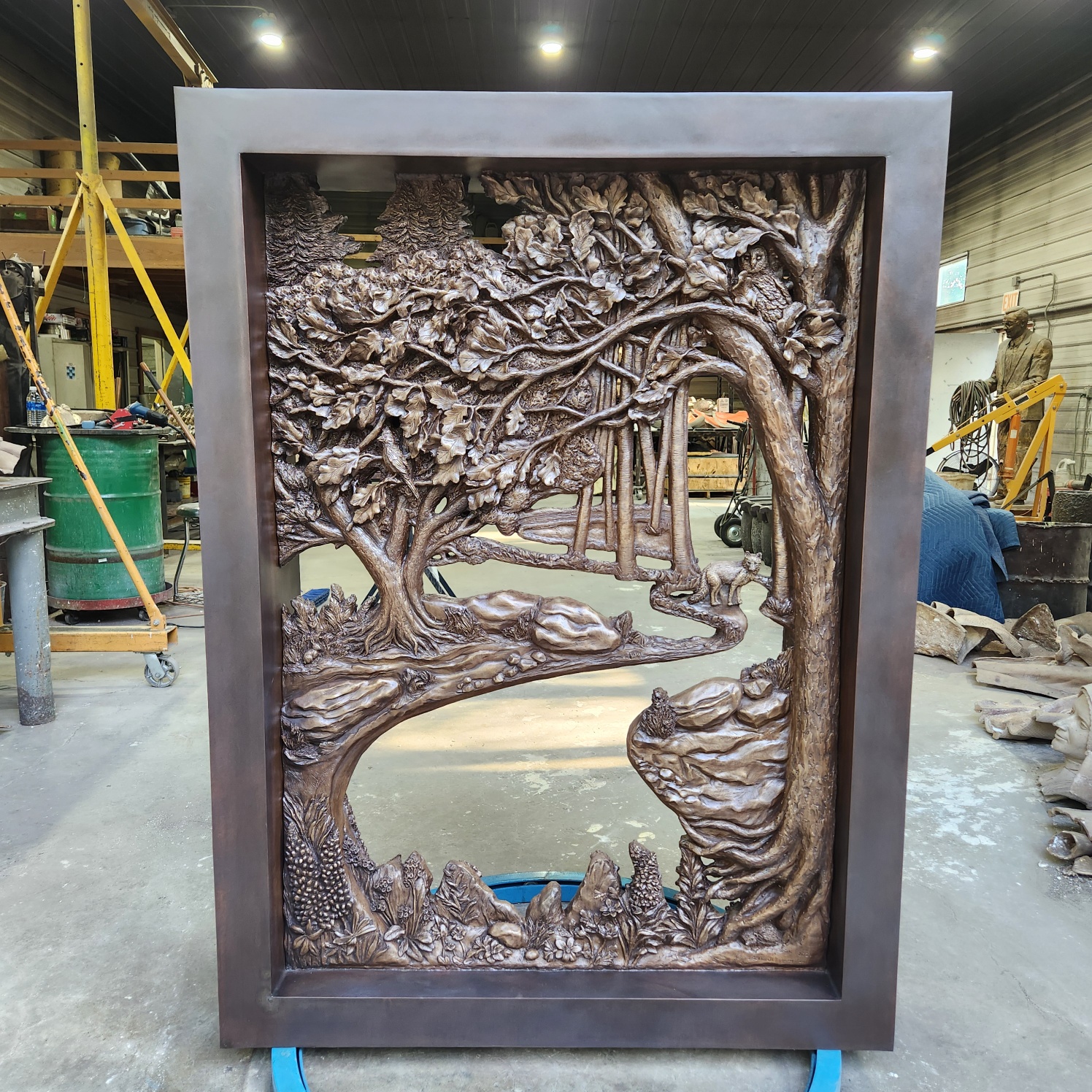 Bronze sculpture of an intricate forest scene with trees, owl, fox, and woodland plants in a rectangular frame.