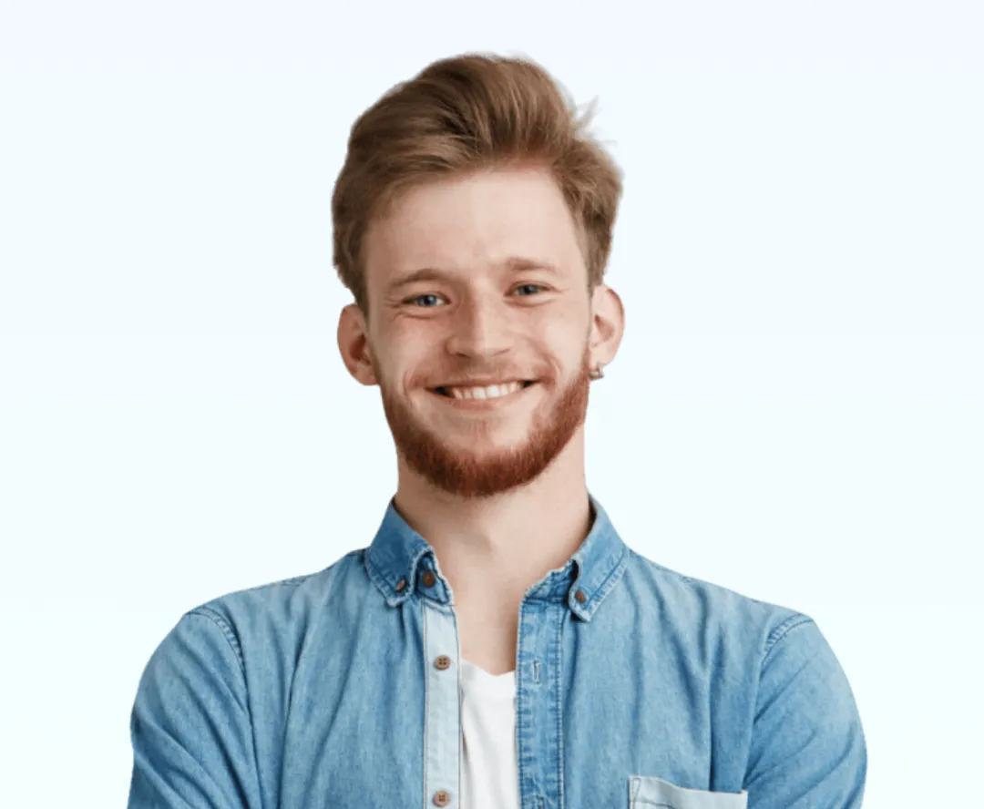 Smiling young man with light brown hair and a beard wearing a blue denim shirt over a white t-shirt.