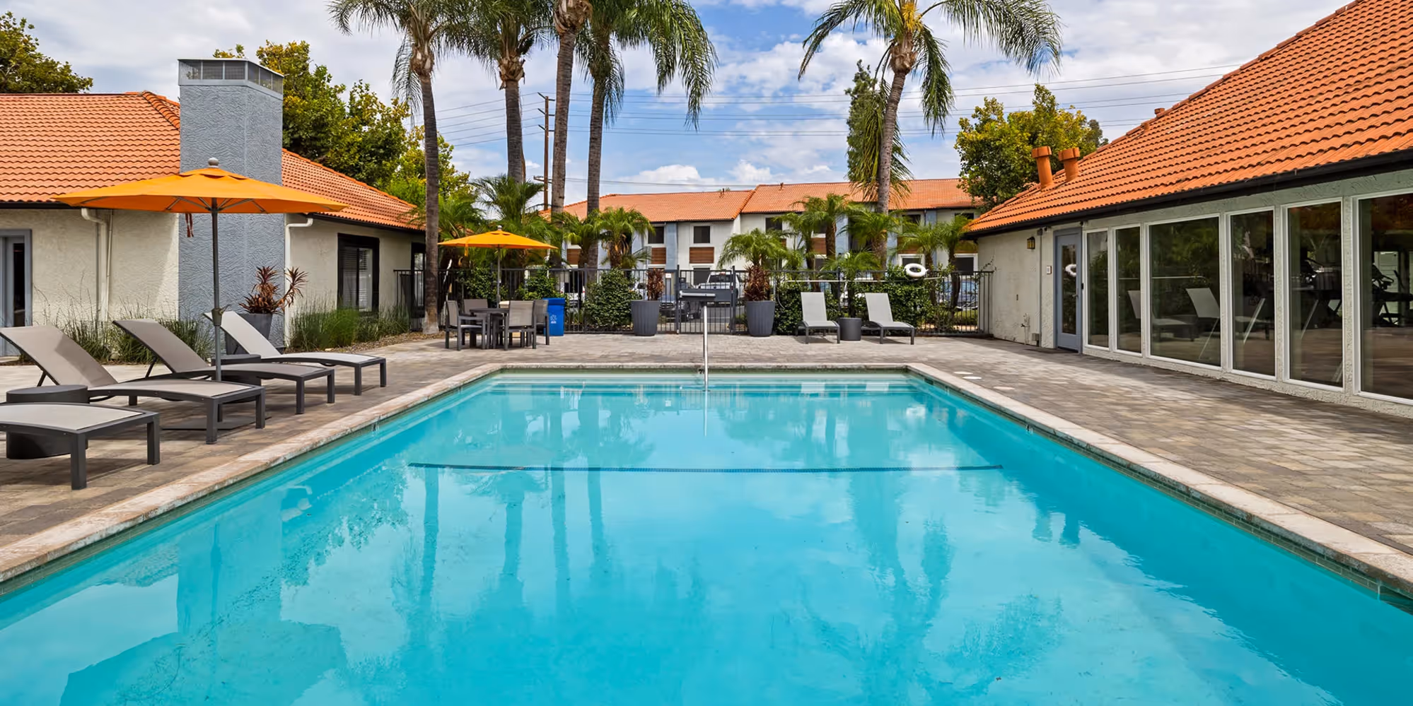Pool with outdoor seating and apartments in the back