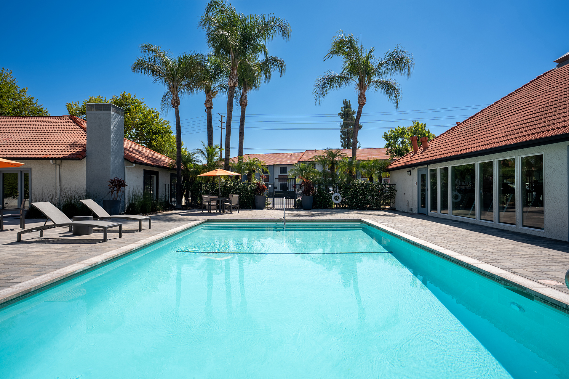 Pool with outdoor seating and apartments in the back