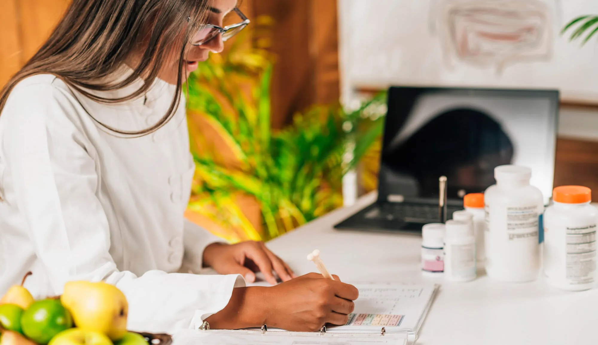 healthcare practitioner sitting at a desk reading a medical chart.