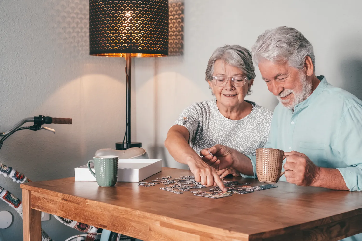 Older couple working on a jigsaw puzzle together at a wooden table at home